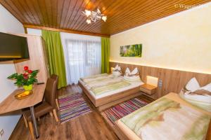 a room with two beds and a table and a desk at Pension Montana in Wagrain