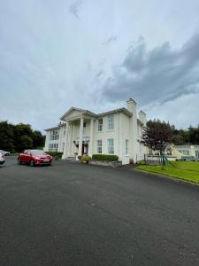 ein weißes Haus mit einem roten Auto davor geparkt in der Unterkunft Redgate House Bed & Breakfast in Derry Londonderry