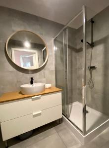 ein Bad mit einem Waschbecken und einer Dusche mit einem Spiegel in der Unterkunft Warsaw Concierge Fabryka na Pradze in Warschau