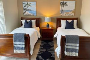 a bedroom with two beds and a table with a lamp at Dockside Destiny in St. Pete Beach