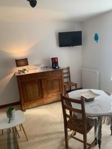 a living room with a table and chairs and a tv at La maison bleue in Remoncourt