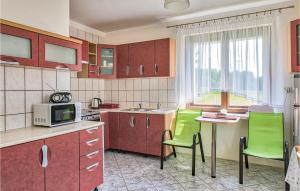 a kitchen with red cabinets and green chairs at 7 Bedroom Lovely Home In Pasym in Pasym