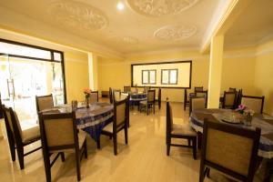 a restaurant with tables and chairs in a room at Sugam Resort & Convention Centre in Chennai