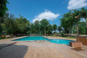 a swimming pool in a park with trees at Sugam Resort & Convention Centre in Chennai