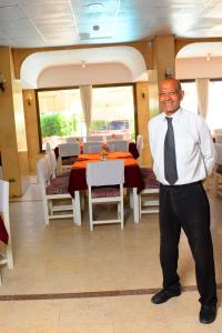 a man in a tie standing in front of a dining room at Shady Hotel Luxor in Luxor