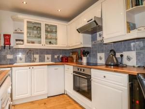 a kitchen with white cabinets and a stove top oven at Padstowgetaways in Padstow
