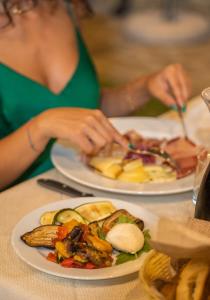 a woman sitting at a table with two plates of food at Le Querce Farmhouse in Agropoli