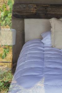 1 cama grande con sábanas y almohadas blancas en Hotel de Tierra Viñedo y Spa - Aeropuerto Querétaro, en San Vicente