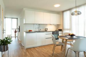 a kitchen with white cabinets and a table and chairs at Wohlfühlapartments in Hard in Hard