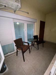 ein Wohnzimmer mit einem Tisch, Stühlen und einem Fenster in der Unterkunft GOLD LUXURY APARTMENT in Kumanovo
