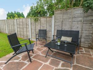 un patio con 2 sillas y una mesa con una botella de vino en 3 Eden View, en Penrith