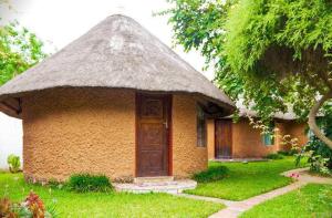 a small house with a grass roof and a door at REED MAT LODGE in Lusaka