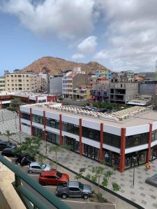 un grand bâtiment blanc avec des voitures garées dans un parking dans l'établissement Appart Hotel Belvedere, à Praia