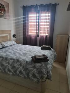 1 dormitorio con 1 cama y una ventana con cortinas en Las Brisas en Granadilla de Abona