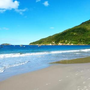 a beach with the ocean and a hill at Katsbarnea Hostel in Florianópolis +82 photos