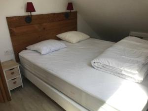 a bed with white sheets and pillows on it at Appartement 6 personnes station de ski Val Louron in Val Louron