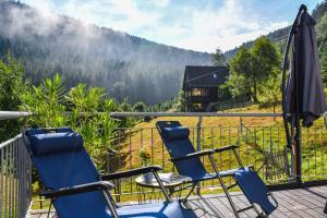 Duas cadeiras e um guarda-sol numa varanda com vista em Ferienhaus Müllerswald em Schenkenzell