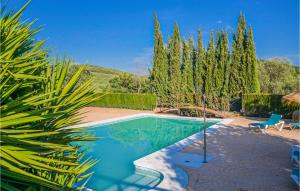 een zwembad in een tuin met een stoel en bomen bij 1 Bedroom Amazing Home In Estepa in Estepa