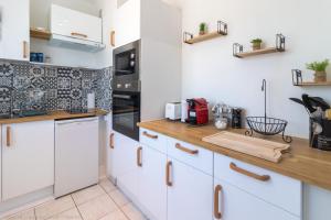 uma cozinha com armários brancos e um balcão de madeira em ZenBNB - L'émeraude - Beautiful Studio Apartment - Near Tram Station for Geneva em Annemasse