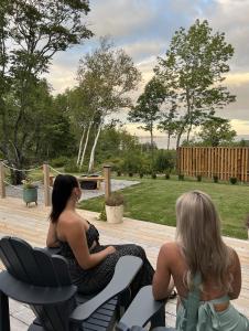 Dos mujeres sentadas en sillas en un patio en Geodome water view stay on Grand Manan Island, en Castalia