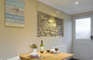 a table with a bottle of wine and two glasses at Broadhaven Cottage, Freshwater East, Pembs in Pembroke