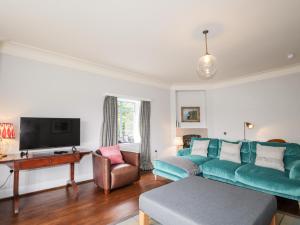 a living room with a blue couch and a tv at Inverewe - House Apartment in Achnasheen