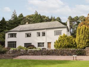 a white house with a stone wall at Inverewe - House Apartment in Achnasheen