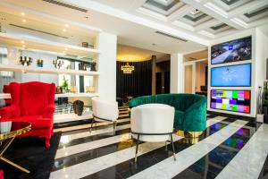 a lobby with red and white chairs and a flat screen tv at Hotel Philosophy in Amman