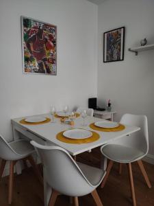 a dining room table with white chairs and a table with glasses at *Street Clichy Art* - Appartement à 200 m de Paris ! in Clichy