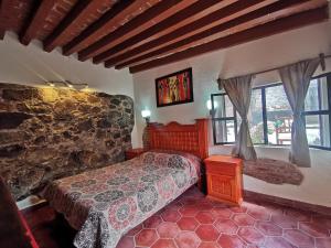 a bedroom with a bed and a stone wall at La Casa del Abuelo in San Miguel de Allende