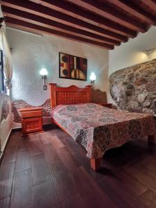 a bedroom with a bed and a stone wall at La Casa del Abuelo in San Miguel de Allende