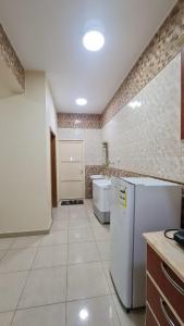 a large kitchen with a refrigerator and a sink at AL Ibdaa Compound Furnished Apartments in Baish