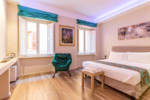a bedroom with a bed and a green chair at La Romantica camere e wellness in Senigallia