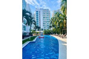 a pool with chairs and palm trees in a resort at Depto 2 Pisos, Vista Alberca. A 50 mts Del Mar in Nuevo Vallarta 