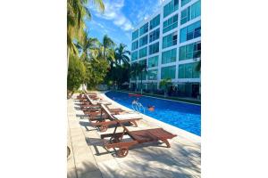 a row of benches next to a building with a swimming pool at Depto 2 Pisos, Vista Alberca. A 50 mts Del Mar in Nuevo Vallarta 