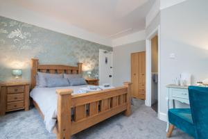 a bedroom with a wooden bed and a blue chair at The Clayton Guest House in Stratford-upon-Avon