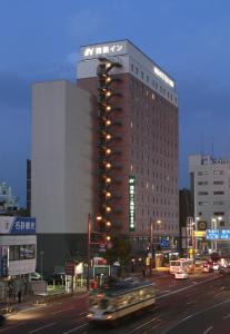 a building with a sign on top of it on a city street at Nishitetsu Inn Kochi Harimayabashi in Kochi