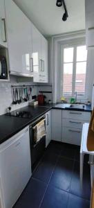 a kitchen with white cabinets and black counter tops at *Street Clichy Art* - Appartement à 200 m de Paris ! in Clichy