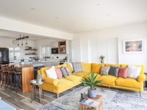 a living room with a yellow couch and a kitchen at Upper Trem Y Borth in Pwllheli