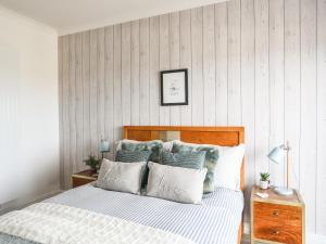 a bedroom with a bed with white and blue pillows at Upper Trem Y Borth in Pwllheli