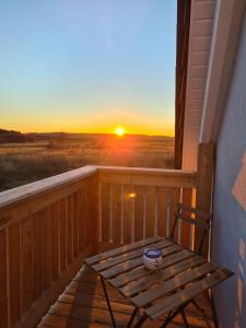 a wooden balcony with a wooden chair and a sunset at Ferienwohnung LOUISE in Dreschvitz