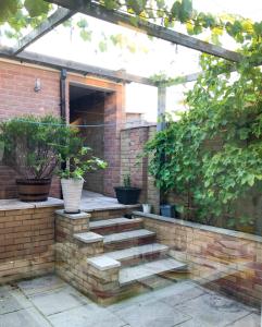 a patio with a brick wall and stairs with potted plants at Corbridge Road in Reading