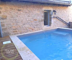 a large blue swimming pool next to a stone wall at L'authentique Martelaise PISCINE CHAUFFEE in Martel
