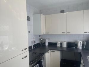 a kitchen with white cabinets and a black counter top at Beautiful 2-bedroom in Grays close to Lakeside in Grays Thurrock