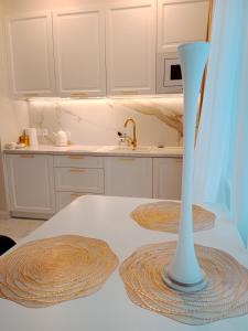 a kitchen with white cabinets and a white vase on a table at Apartament Glamour Chełm in Chełm