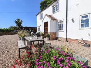 a patio in front of a white house with flowers at Rose Cottage in Louth