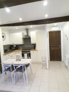 a kitchen with white cabinets and a table and chairs at Maison de L'Amour Apartment Chardonnay in Assignan