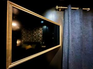 un miroir suspendu sur un mur à côté d'un rideau dans l'établissement Love Room Secrète Les Petits Plaisirs, à Angers