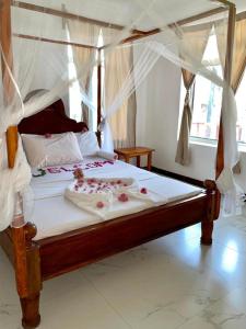 a bedroom with a canopy bed with flowers on it at Mambo Boutique Nungwi in Nungwi