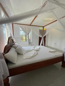 ein großes Bett mit Baldachin in einem Zimmer in der Unterkunft Mambo Boutique Nungwi in Nungwi